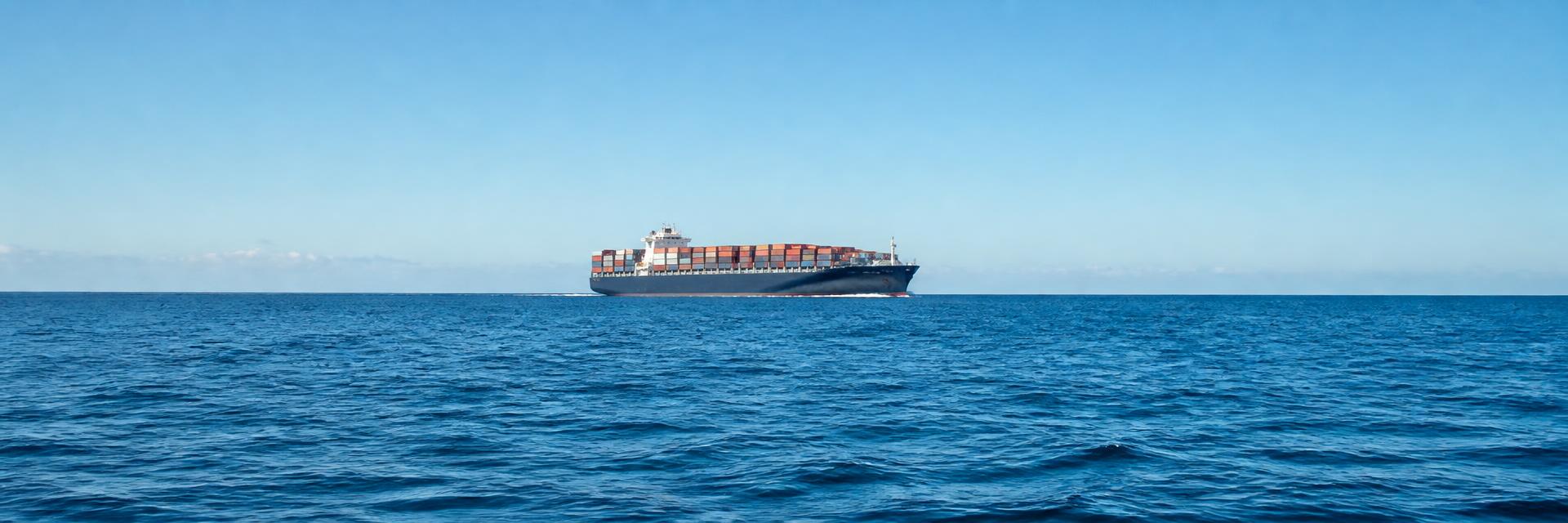 Container vessel sailing on open blue ocean water under a clear sky